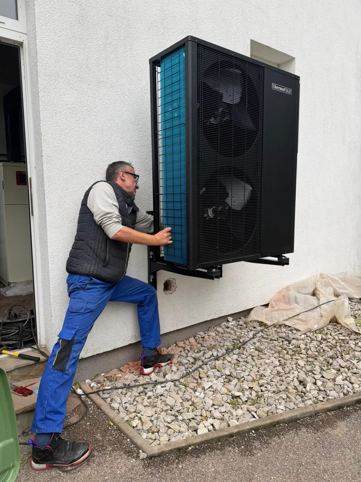 Monter postavlja vanjsku jedinicu ThermoFLUX toplotne pumpe na zidne nosače